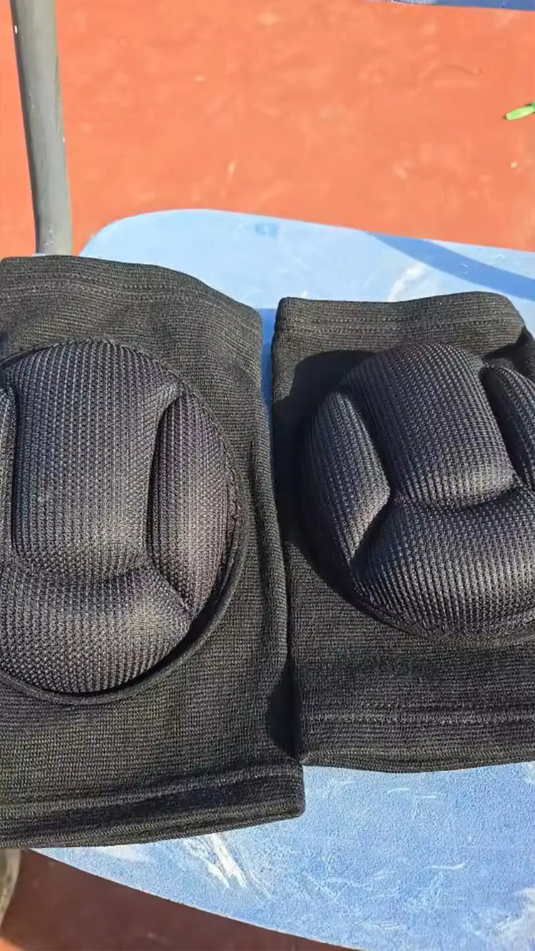 Pair of black knee pads on a blue surface with an orange background