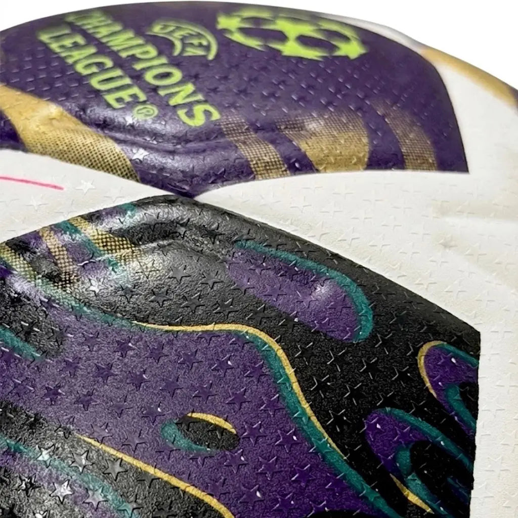 Close-up of a sports ball with purple, black, and gold design, featuring 'UEFA Champions League' branding.