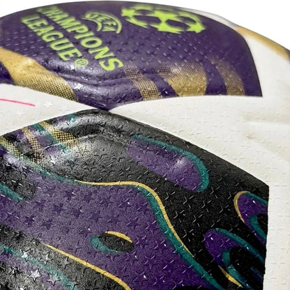 Close-up of a sports ball with purple, black, and gold design, featuring 'UEFA Champions League' branding.